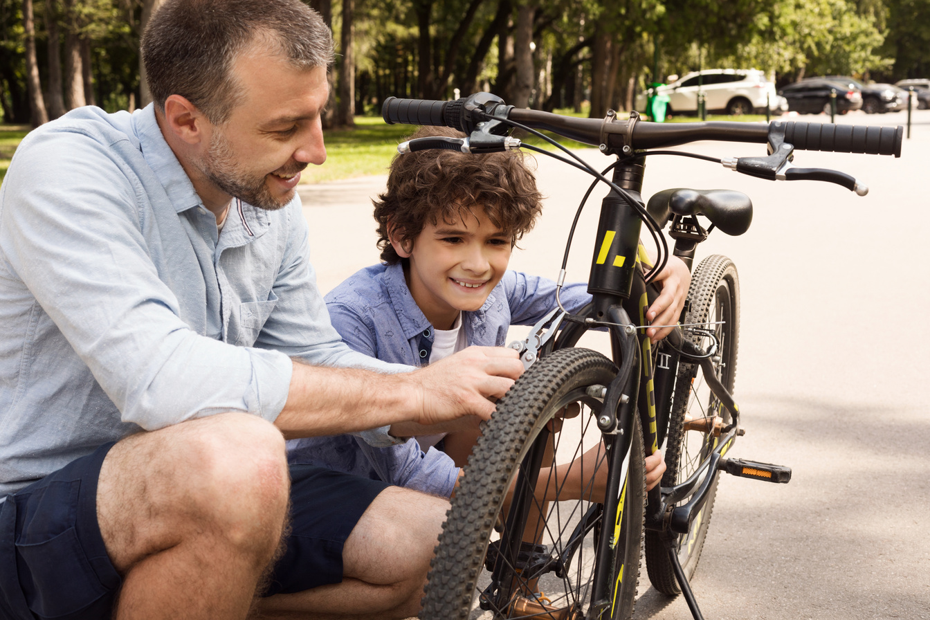 Closeup portrait of cheerful dad and son fixing bike